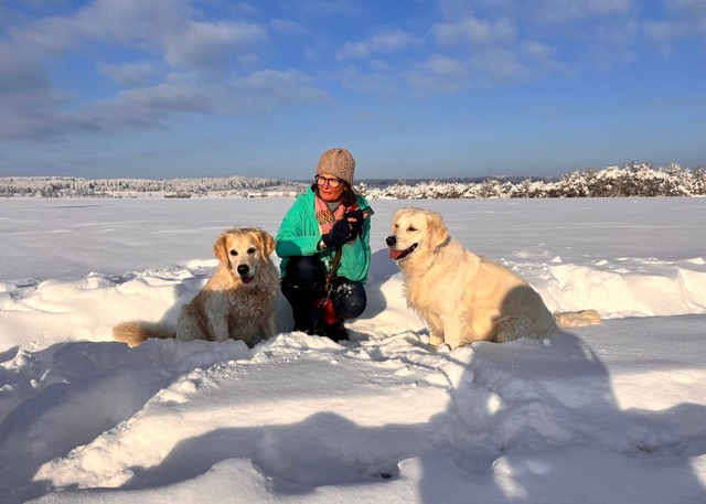 Frau mit zwei Hunden im Schnee.