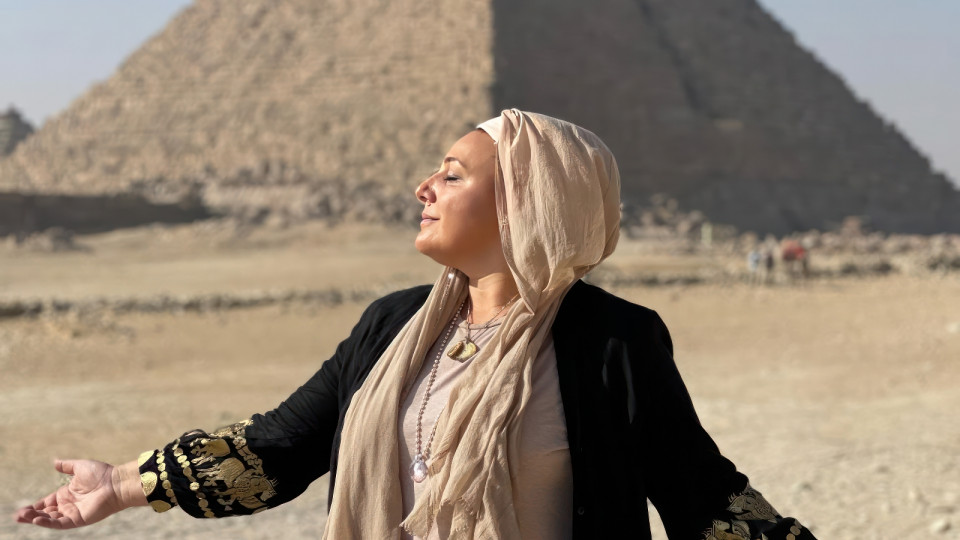 Za Rah Kumara steht vor einer ägyptischen Pyramide und trägt ein erdfarbenes Gewandt.